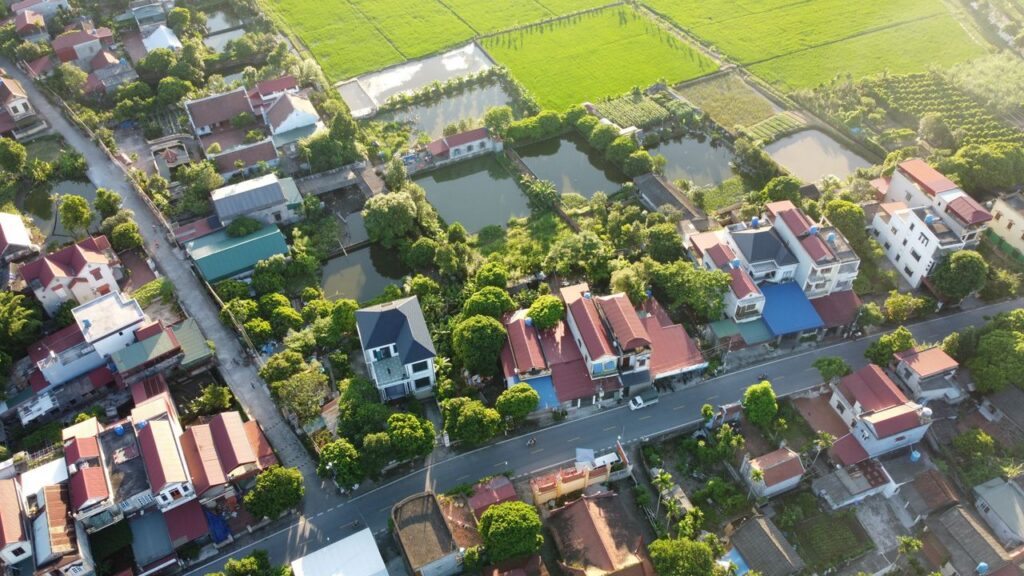 Scenic aerial shot of a lush Vietnamese village with greenery and water bodies.