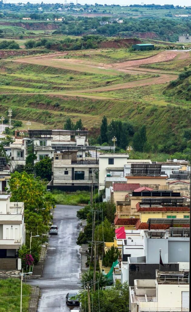 Urban neighborhood blending with lush green fields under a cloudy sky, showcasing suburban living.